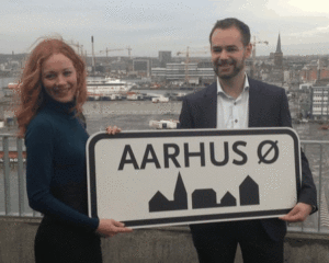 Venstres Laura Hay og socialdemokraternes borgmester Jacob Bundsgaard med navnet på den nye bydel, der skyder op på havnen bag dem de kommende år. (© Aarhus Kommune)